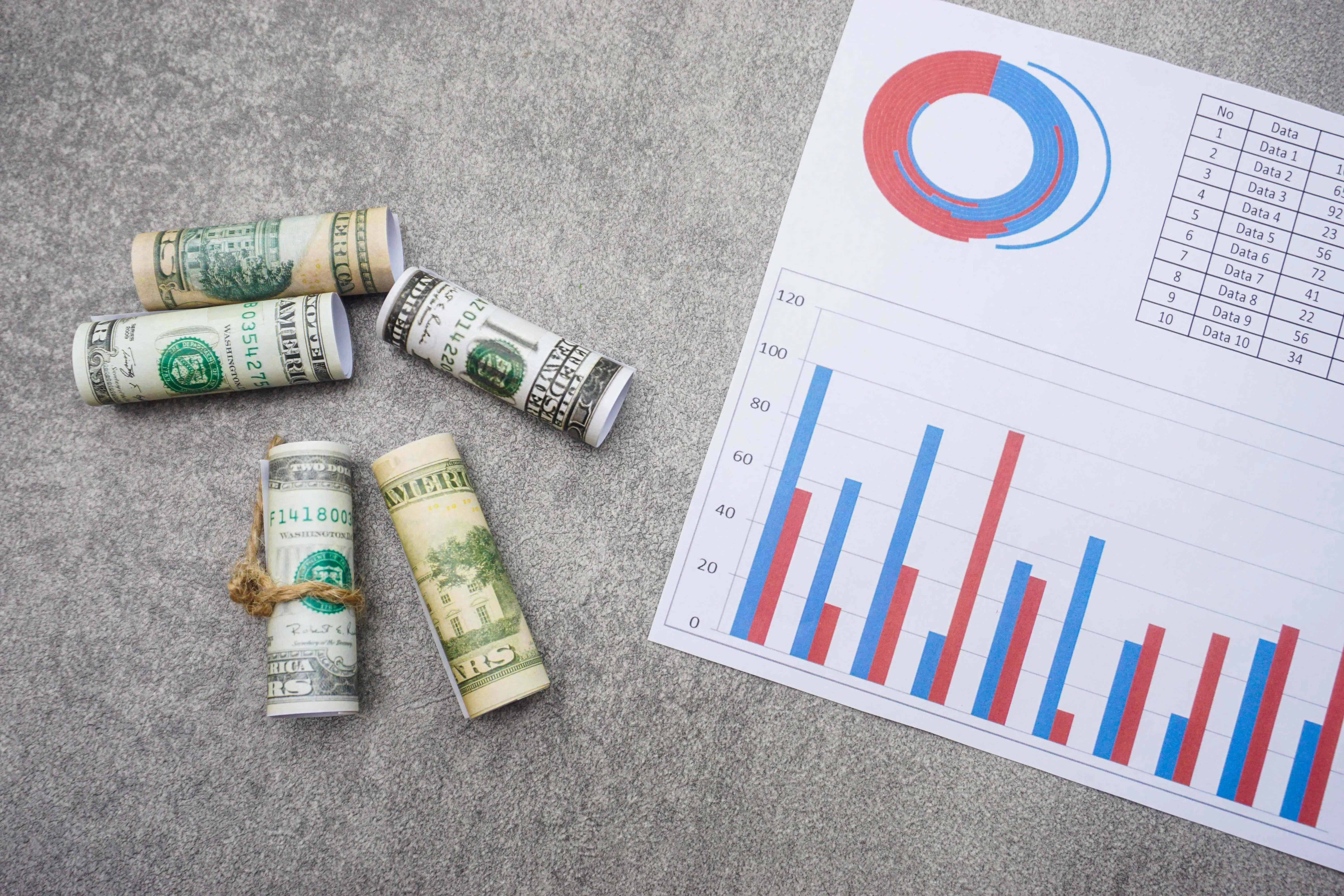 flat-lay-of-rolled-dollar-bills-and-a-paper-with-c-2023-11-27-05-32-11-utc